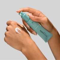3 pieces of Hydropeptide Anti-Wrinkle + Clarify skincare in teal green bottles coming out of a splash of water